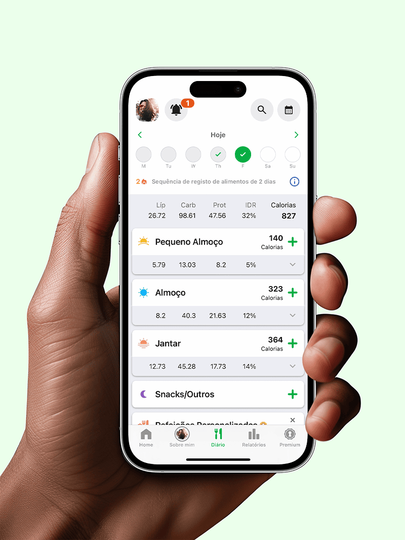 Man's hand holding mobile phone that shows fatsecret app diary screen showing food logged against breakfast and lunch.
